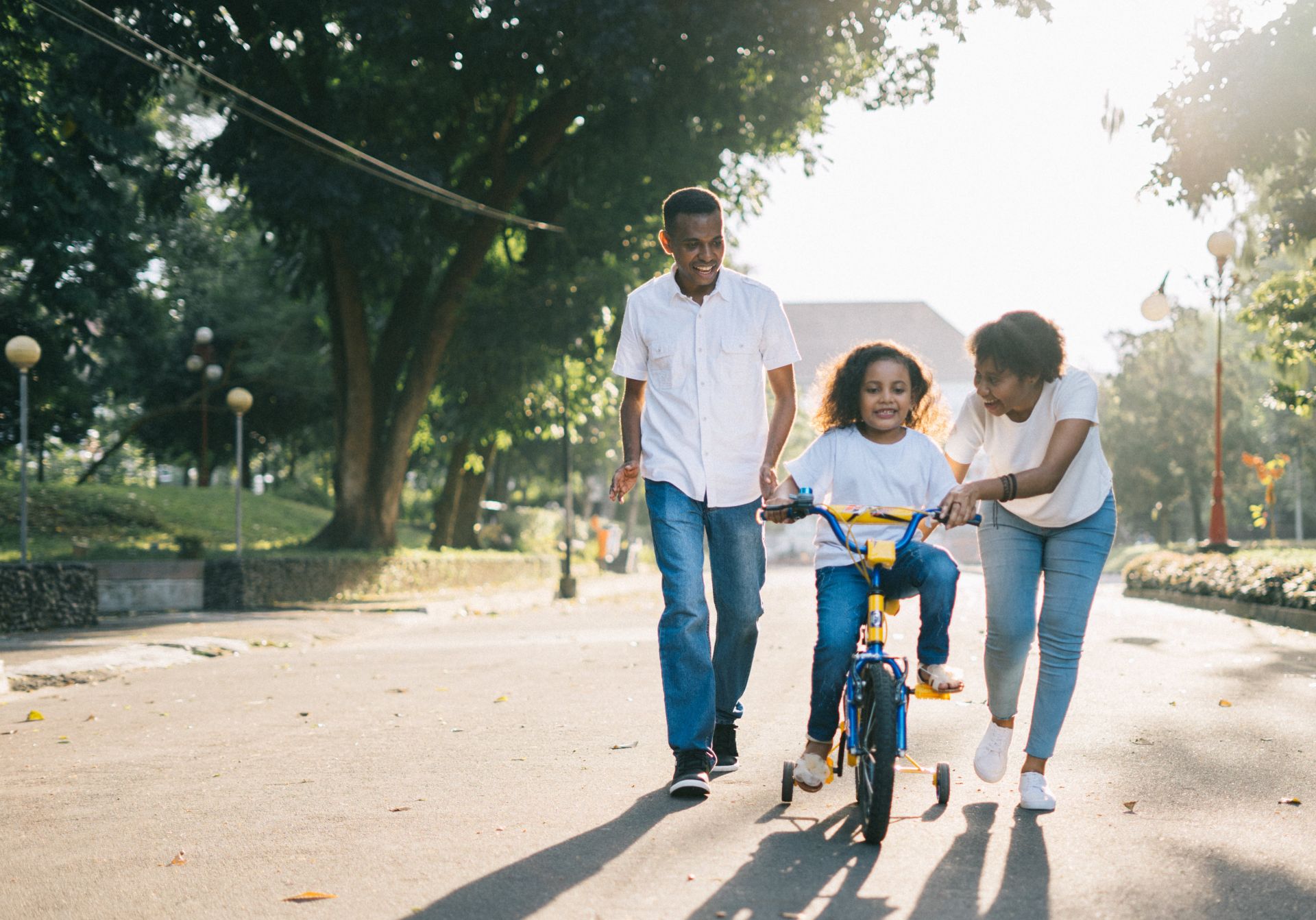 Man Standing Beside His Wife Teaching Their Child How to Ride Bicycle